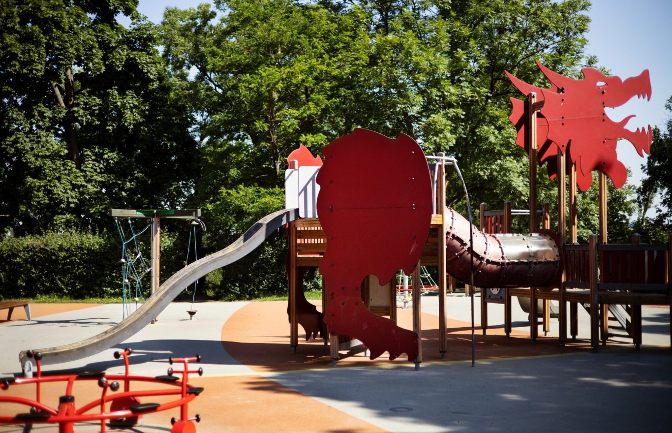 Hof mit Spielplatz, Rutsche und modernen Wohngebäuden im Hintergrund. Moderner Spielplatz, Rutsche, Sandkasten
