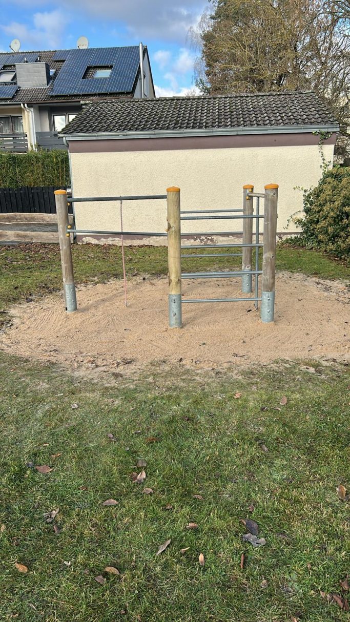 Freibadspielplatz mit Sandfläche und Holzstruktur für Kinder.